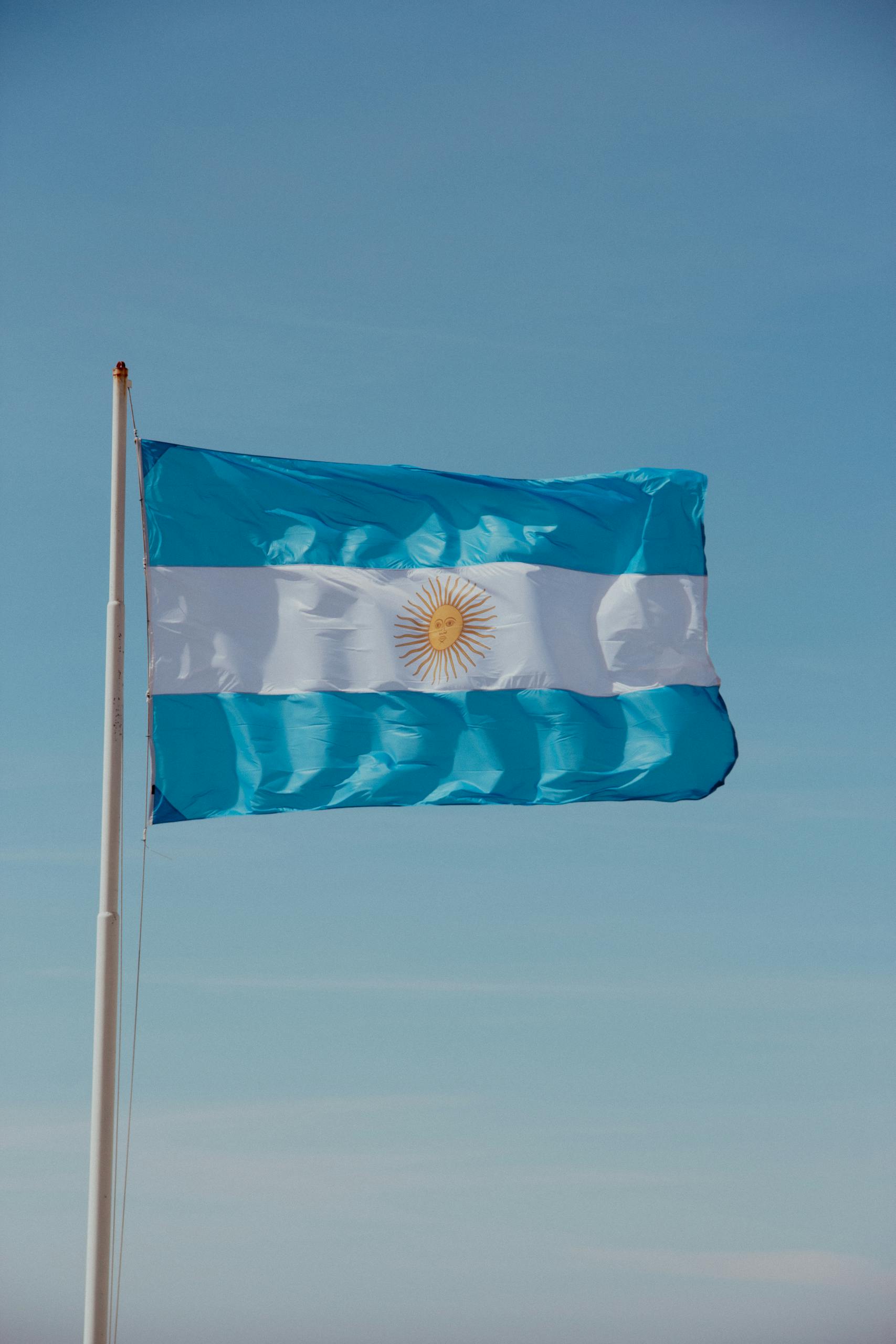A vibrant Argentinian flag flutters in the clear blue sky, symbolizing national pride.